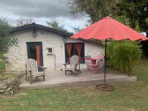 a wooden deck with a table and chairs and an umbrella at Le petit lodge cosy in Saint-Savinien