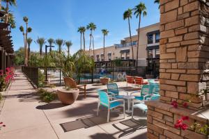 d'une terrasse avec des chaises, des tables et des palmiers. dans l'établissement Hampton Inn & Suites Scottsdale On Shea Blvd, à Scottsdale