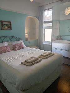 ein Schlafzimmer mit einem weißen Bett und Handtüchern darauf in der Unterkunft Ocean City Apartment-with parking in Plymouth