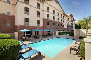 una piscina frente a un edificio con sillas y sombrillas en Hampton Inn Phoenix Midtown Downtown Area en Phoenix