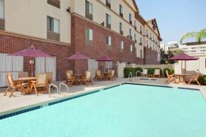 a swimming pool with chairs tables and umbrellas next to a building at Hampton Inn Phoenix Midtown Downtown Area in Phoenix