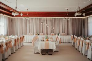 - une salle de banquet avec des tables et des chaises blanches dans l'établissement Csikar Csárda és Panzió, à Kőszeg