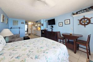 1 dormitorio con paredes azules, 1 cama y 1 mesa en Pirates Cove Condo Unit #511 en Daytona Beach Shores