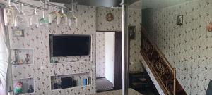 a room with a tv on a wall with a staircase at Дача Уют Чарвак in Chorwoq