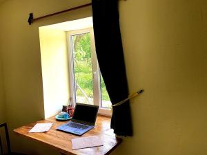 einem Laptop auf einem Schreibtisch vor einem Fenster in der Unterkunft Old Farm in Idschewan