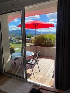 un patio con una mesa y una sombrilla roja en FalHappy House, en Poisy