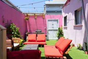 a patio with red chairs and a pink wall at Ajami Guest House in Tel Aviv