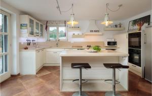 a kitchen with white cabinets and a island with two bar stools at Villa Stella Maris in Suđurađ