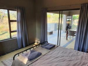 1 dormitorio con cama y vistas a un patio en Horizon Savannah, en Dinokeng Game Reserve