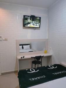 a room with a desk with a tv on the wall at Cahaya Losmen Sragen in Sragen