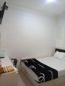 a bedroom with a bed with a black and white blanket at Cahaya Losmen Sragen in Sragen