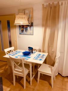une table à manger avec des chaises blanches et un lustre dans l'établissement Hiška on the cliff, à Ankaran