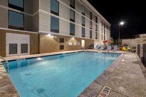 Home2 Suites by Hilton Gulf Breeze Pensacola Area, FL في غولف بريز: مسبح كبير امام الفندق في الليل