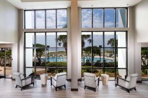 a lobby with windows and chairs and a pool at The Island House Hotel a Doubletree by Hilton in Orange Beach