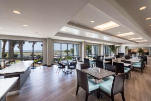 ein Restaurant mit Tischen, Stühlen und Fenstern in der Unterkunft The Island House Hotel a Doubletree by Hilton in Orange Beach