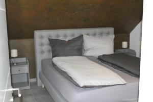 ein Bett mit weißer Bettwäsche und Kissen darauf in der Unterkunft Ferienwohnungen am Playmobilpark in Oberasbach