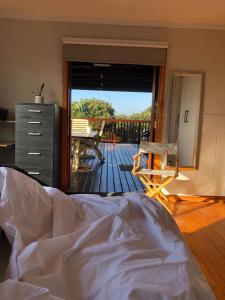a bedroom with a bed and a deck with a patio at Log Cabin By The Beach in Port Edward