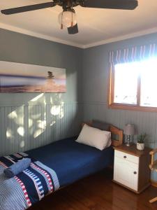 a bedroom with a bed and a ceiling fan at Log Cabin By The Beach in Port Edward