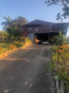 a house with a car parked in a driveway at Log Cabin By The Beach in Port Edward