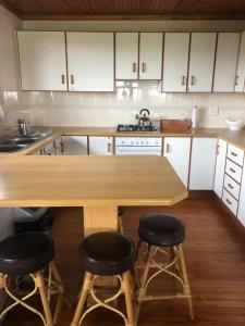 a kitchen with a wooden table and four bar stools at Log Cabin By The Beach in Port Edward