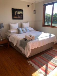 a bedroom with a large bed with towels on it at Log Cabin By The Beach in Port Edward