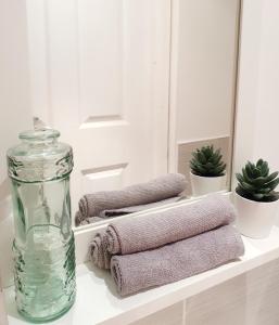 a white shelf with towels and a glass bottle at West Park Annex Central Wolverhampton in Wolverhampton