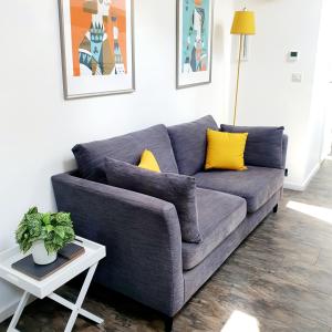 a gray couch with yellow pillows in a living room at West Park Annex Central Wolverhampton in Wolverhampton