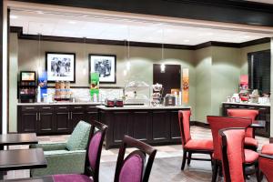 a restaurant with a bar and tables and chairs at Hampton Inn Lewiston-Auburn in Lewiston