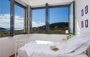 a bedroom with a white bed and large windows at Villa Mar in Lumbarda