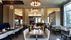 a dining room with tables and chairs and chandeliers at Hilton Garden Inn Freeport Downtown in Freeport