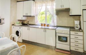 eine Küche mit weißen Schränken, einer Spüle und einem Geschirrspüler in der Unterkunft 4 Bedroom Amazing Apartment In Muros in Muros