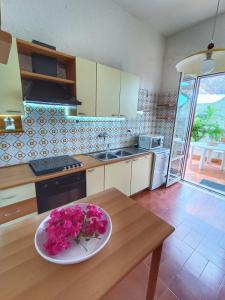 uma cozinha com uma mesa com um prato de flores em Villa Giusi - bifamiliare sul mare em Torregrotta