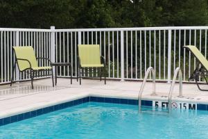 a swimming pool with two chairs and a fence at Hampton Inn & Suites Walterboro in Walterboro