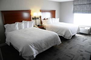 two beds with white sheets in a hotel room at Hampton Inn & Suites Redding in Redding