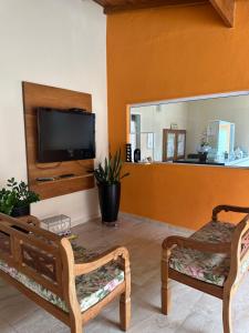 sala de estar con 2 sillas y TV de pantalla plana en Pousada da Praia, en Paraty