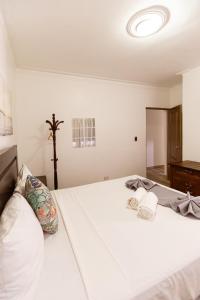 a bedroom with a large bed with white sheets at Hostal Las Rosas de Punta Cana in Punta Cana