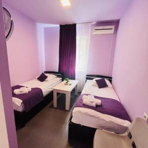 2 bedden in een kamer met paarse muren bij MarNar Hotel in Jerevan