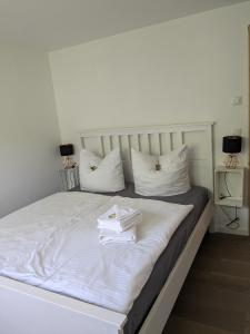 a white bed with white pillows and books on it at Ferienhaus Hellaberg in Langenbach