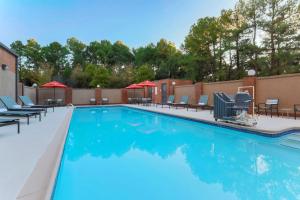 a swimming pool at a resort with chairs and umbrellas at Hilton Garden Inn Raleigh-Durham/Research Triangle Park in Durham