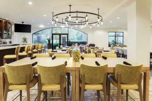 una sala da pranzo con tavoli, sedie e lampadario a braccio di Hilton Garden Inn Raleigh-Durham/Research Triangle Park a Durham