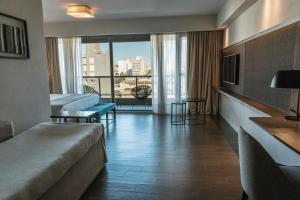 a hotel room with a bed and a balcony at Mulen Hotel Tandil in Tandil