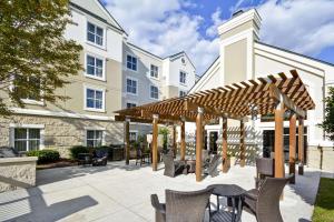 patio ze stołami i krzesłami pod drewnianą pergolą w obiekcie Homewood Suites Durham-Chapel Hill I-40 w mieście Durham