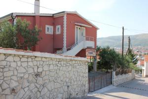una casa roja con una pared de piedra y un edificio en Apartments Toni, en Trogir