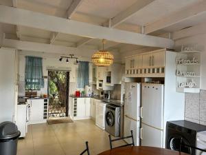 a large kitchen with white appliances and a dining table at Big Fish Seaside Cottage, sleeps 10 Guests in 5 Bedrooms in Port Edward