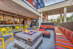 Home2 Suites By Hilton Raleigh State Arena في رالي: فناء مع كراسي ملونة وحفرة نار