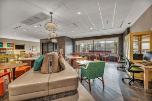 Home2 Suites By Hilton Raleigh State Arena في رالي: مكتبة فيها طاولات وكراسي كنب