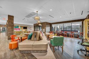 a waiting room with a couch and tables and chairs at Home2 Suites By Hilton Raleigh State Arena in Raleigh