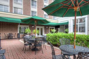 a patio with tables and chairs with green umbrellas at Hilton Garden Inn Durham Southpoint in Durham