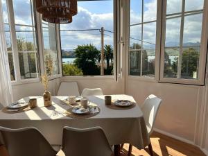 - une salle à manger avec une table, des chaises et des fenêtres dans l'établissement El Faro de la Barquera, à San Vicente de la Barquera