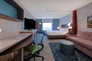 a hotel room with a bed and a living room at Home2 Suites By Hilton DeKalb in DeKalb